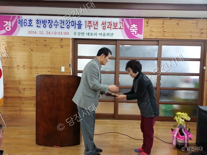 한 남성이 한방장수건강마을 1주년 성과보고회에서 상장을 수여하고 있다.