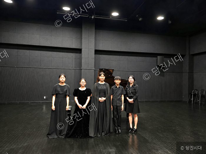 당진 라온피아노학원 원생들과 강사가 무대 위에서 포즈를 취하고 있다.