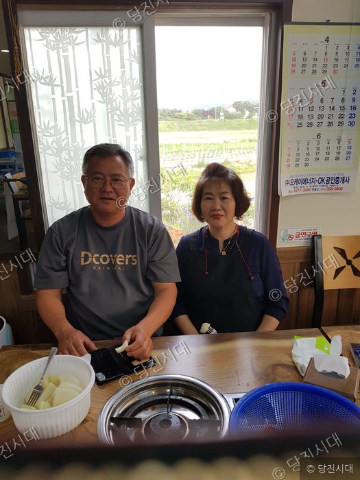 식당을 운영하는 남매가 테이블에 앉아 포즈를 취하고 있다.