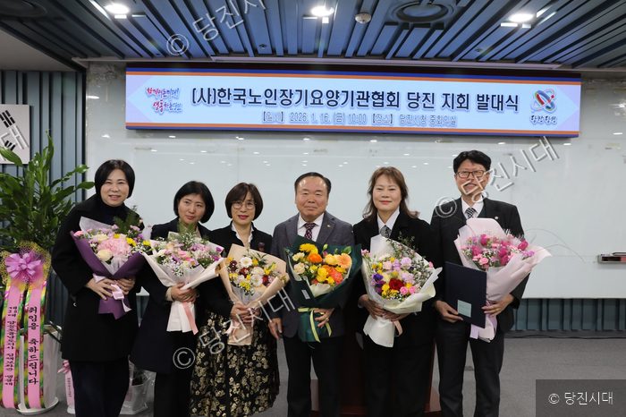 참석자들이 (사)한국노인장기요양기관협회 당진지회 발대식에서 꽃다발을 들고 기념촬영을 하고 있다.
