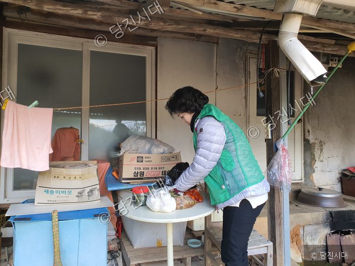 봉사자가 시골 주택 마당에서 준비해 온 물품을 정리하고 있다.