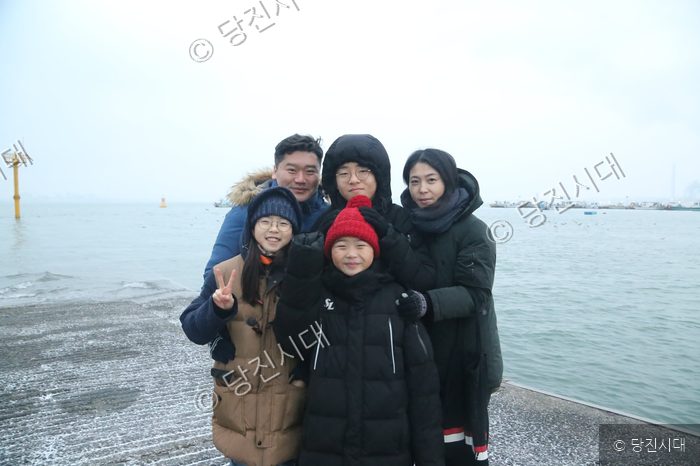 윤동희 가족이 바닷가를 배경으로 기념사진을 찍고 있다.
