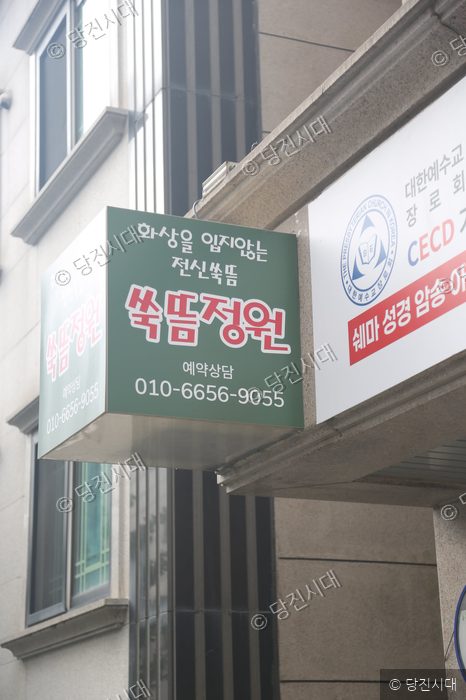 건물 외벽에 부착된 쑥뜸정원 간판과 안내판이 보인다.