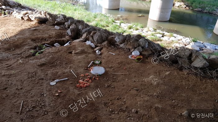 하천변 산책로 주변 공터에 쓰레기가 무단으로 버려져 있다.