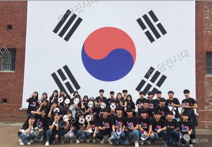 송악고등학교 학생들이 태극기 앞에서 기념촬영을 하고 있다.