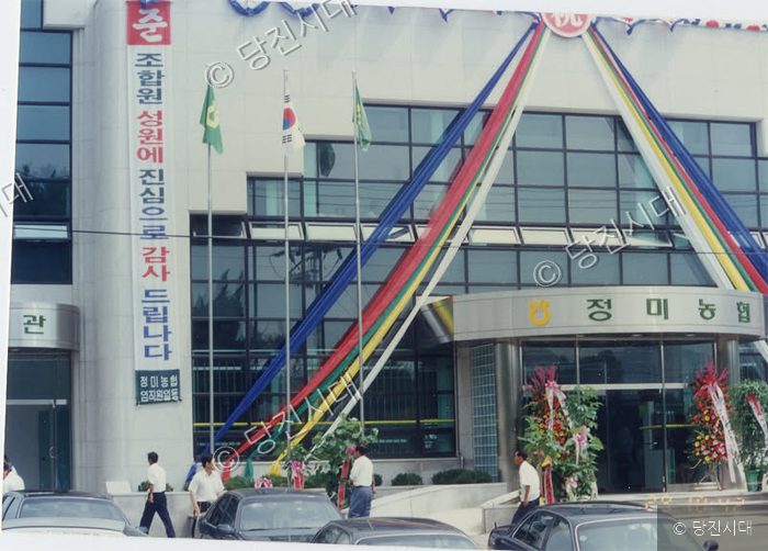 정미농협 준공식 행사장에서 사람들이 건물을 배경으로 서 있다.