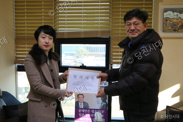 두 사람이 항의서한을 전달하고 있다.