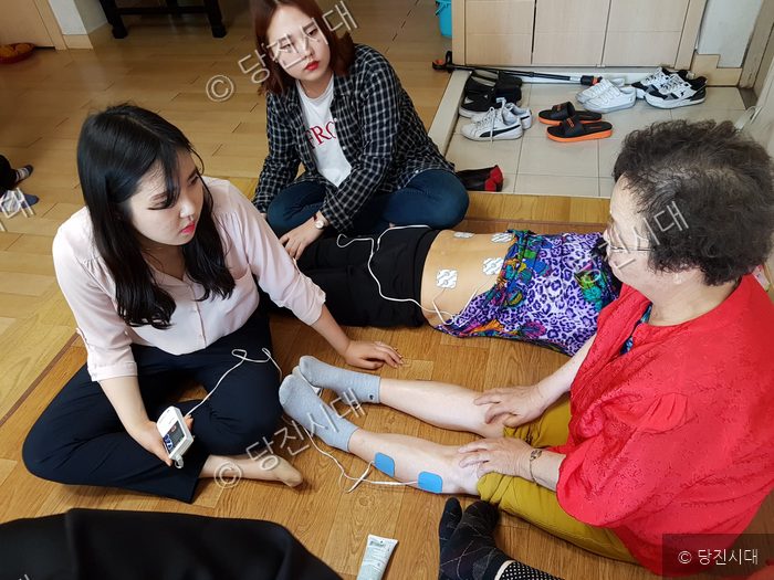 봉사자들이 어르신에게 물리치료 봉사활동을 하고 있다.