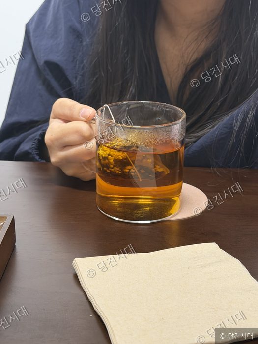조은미 대표가 카페에서 따뜻한 차가 담긴 컵을 손으로 들고 있다.