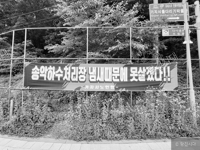 송악하수처리장 악취를 규탄하는 현수막이 거리 울타리에 걸려 있다.