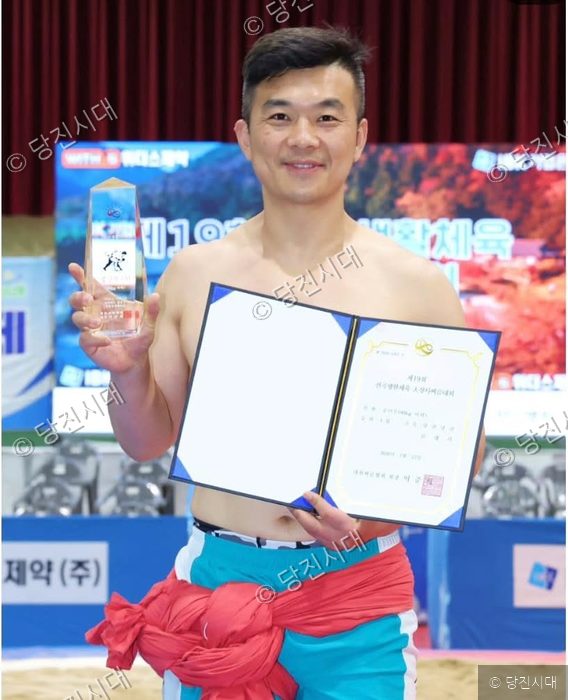 김래석 강사가 전국생활체육 씨름대회에서 우승 후 상장과 트로피를 들고 기뻐하고 있다.