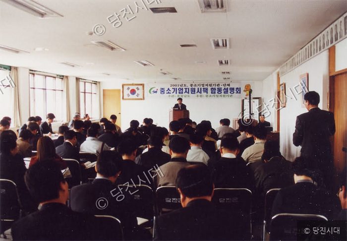 사람들이 강당에 모여 중소기업 지원시책 설명회를 듣고 있다.