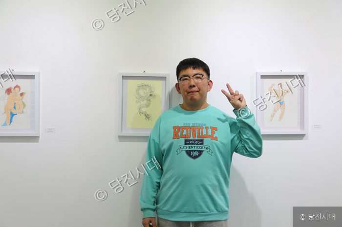 송규민 작가가 자신의 작품 전시회장에서 포즈를 취하고 있다.