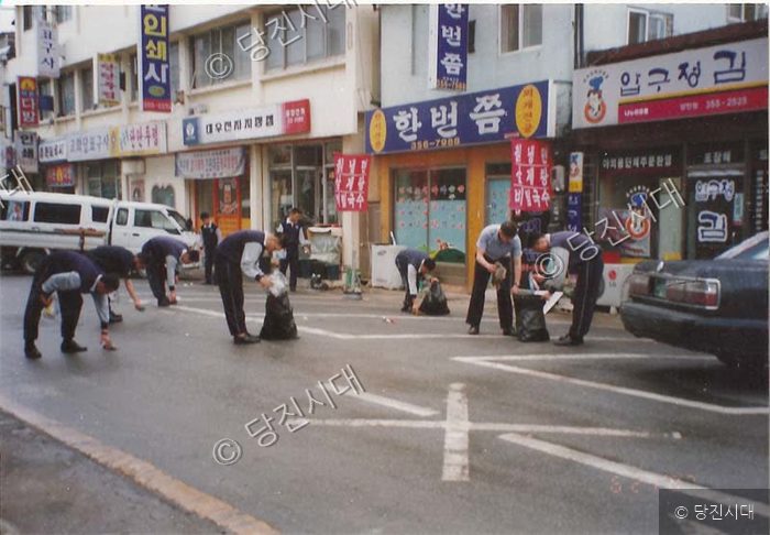 경찰관들이 거리를 청소하며 쓰레기를 줍고 있다.