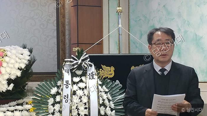 이명남 목사가 종교적 추모 행사에서 종이를 들고 발언하고 있다.