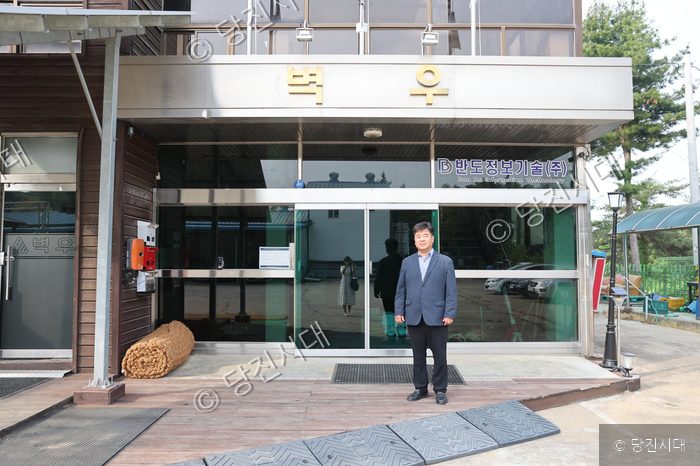 (주)벽우 건물 앞 출입구에서 한기흥 대표이사가 포즈를 취하고 있다.