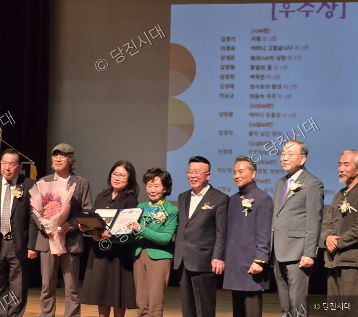 수상자들이 무대 위에서 상장과 꽃다발을 들고 기념 촬영을 하고 있다.