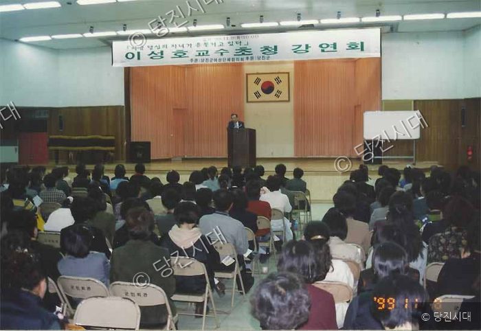 강연회장에서 강사가 연단에서 발표를 하고 있다.