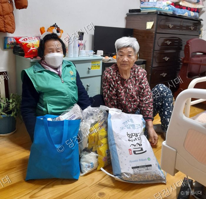 두 어르신이 자택에서 후원 물품을 받고 기념 촬영을 하고 있다.