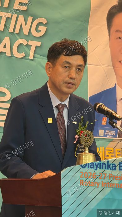 한 남성이 단상에서 로타리클럽 관련 행사를 진행하고 있다.