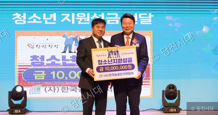 한기흥 대표이사 등이 무대 위에서 청소년 지원성금 보증서를 들고 기념 촬영을 하고 있다.
