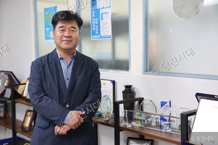 한기흥 대표이사가 사무실 내에 서서 포즈를 취하고 있다.
