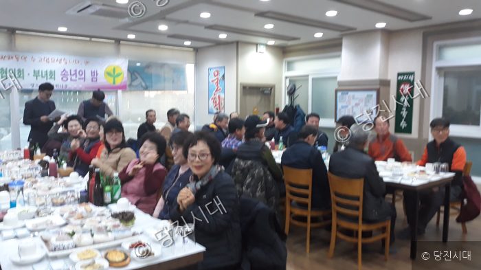 주민들이 식당에 모여 송년의 밤 행사를 진행하고 있다.