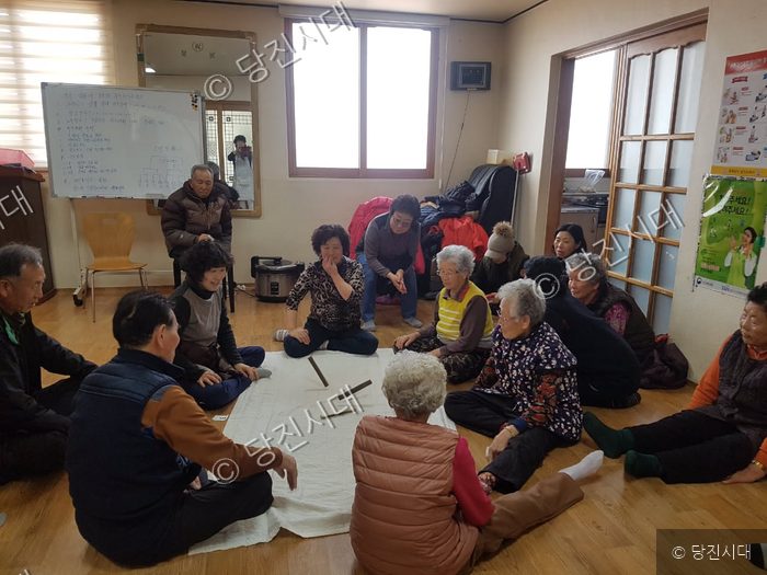 마을 주민들이 모여 실내에서 전통 놀이를 즐기고 있다.