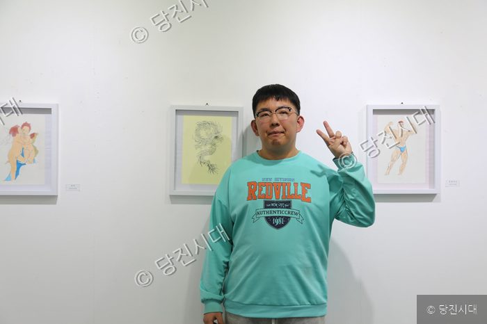 송규민 씨가 자신의 전시 작품 앞에서 포즈를 취하고 있다.