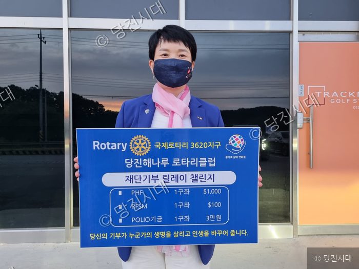 여성이 로타리클럽 기부 챌린지 피켓을 들고 있다.