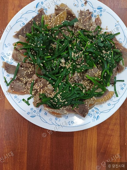 접시에 담긴 수육과 부추무침 요리가 놓여 있다.