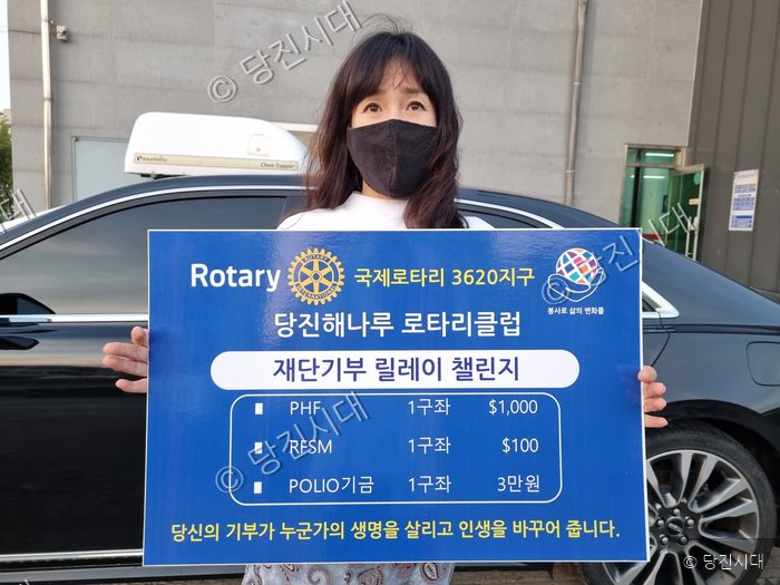 여성이 기부 챌린지 피켓을 들고 서 있다.