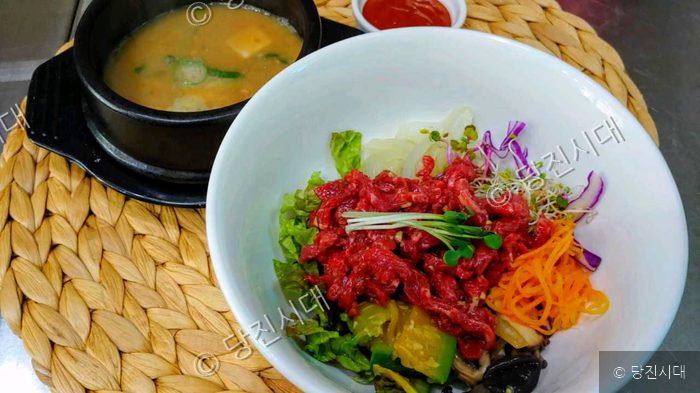 한우육회비빔밥과 청국장이 식탁 위에 놓여 있다.