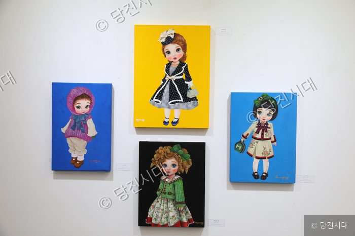 갤러리에 전시된 베이비돌 그림 작품들이 벽면에 걸려 있다.