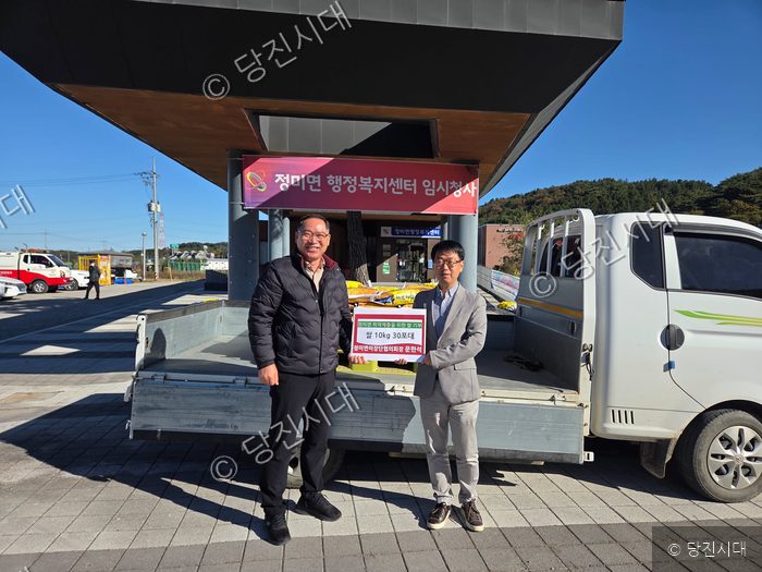 두 남성이 쌀 기탁식을 기념하며 포즈를 취하고 있다