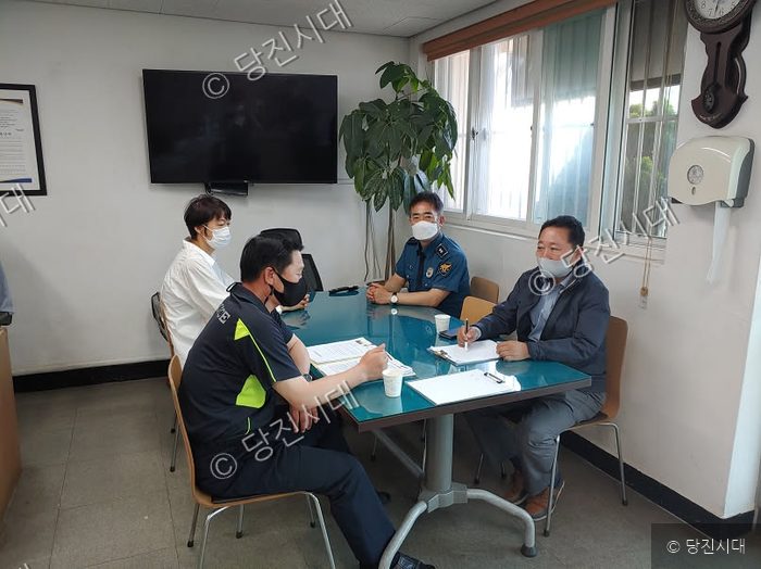 경찰관들과 주민들이 테이블에 둘러앉아 교통사고 예방 간담회를 하고 있다.