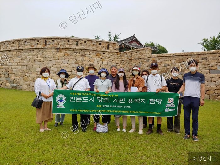 참가자들이 당진의 유적지 앞에서 현수막을 들고 기념 촬영을 하고 있다.
