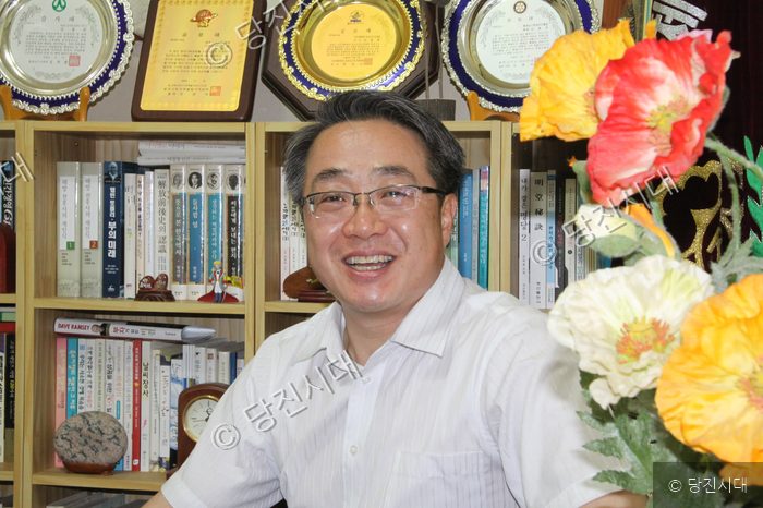 당나루로타리 김용관 회장이 책장 앞에서 미소 짓고 있다.