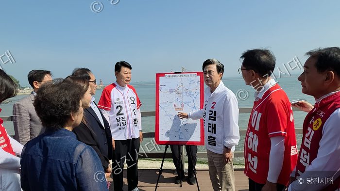 김태흠 후보 등 정치인들이 야외에서 지도를 보며 공약을 설명하고 있다.