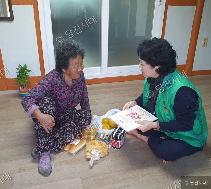 봉사자가 어르신을 찾아가 선물을 전달하고 있다.