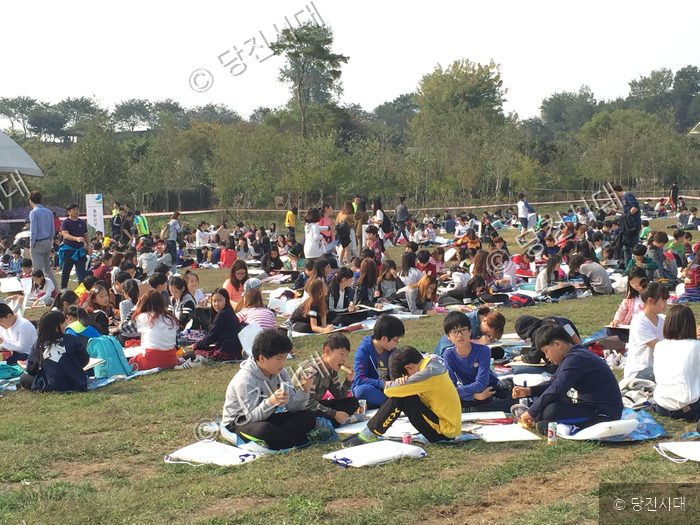 학생들이 잔디밭에 모여 환경사랑 미술대회에 참가하고 있다.