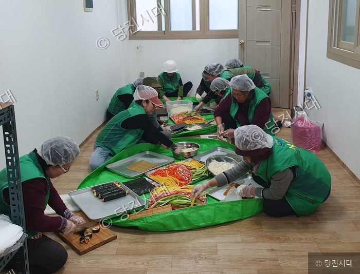 새마을회원들이 모여 김밥을 정성스럽게 만들고 있다.
