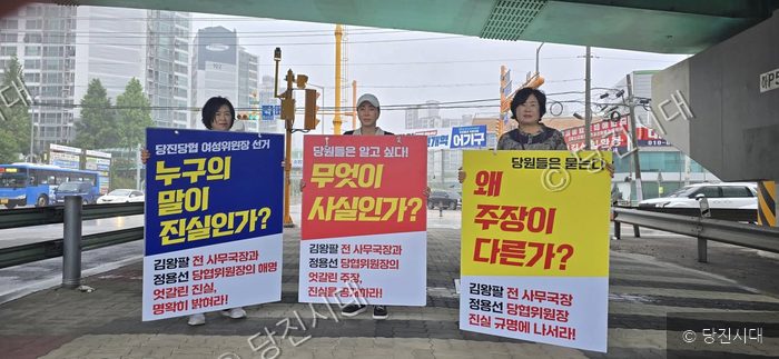 세 명의 여성이 여성위원장 선거 공정성을 촉구하는 피켓 시위를 벌이고 있다.