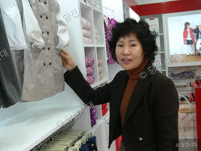 여성 상인인 아동복 전문점 매장에서 옷을 정리하고 있다.