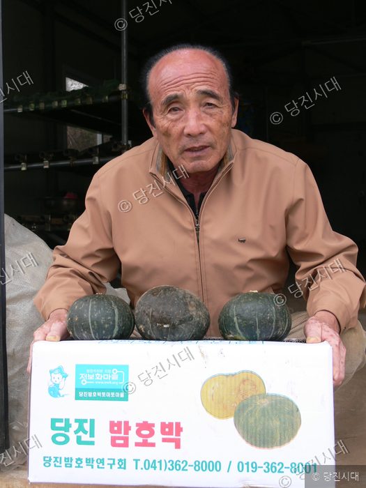한 농민이 자신이 재배한 밤호박 상자를 들어 보이고 있다.