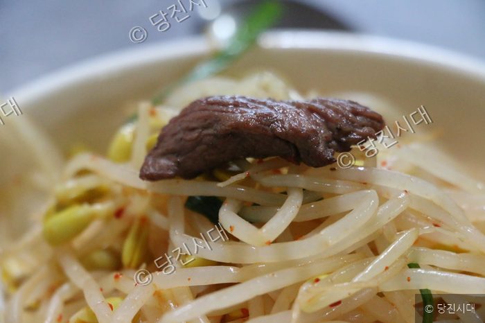 당진갈매기 음식점에서 콩나물과 고기가 접시에 담겨 있다.