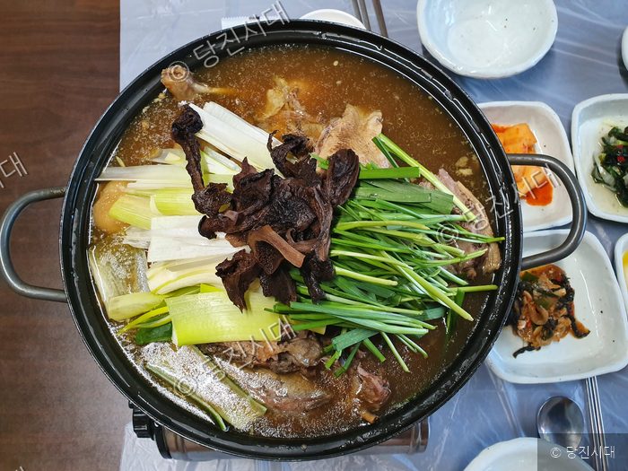 식당 테이블 위에 푸짐하게 차려진 보양식 전골 요리가 놓여 있다.