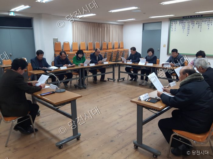 사람들이 회의실에 모여 앉아 문서를 살펴보며 회의를 하고 있다.