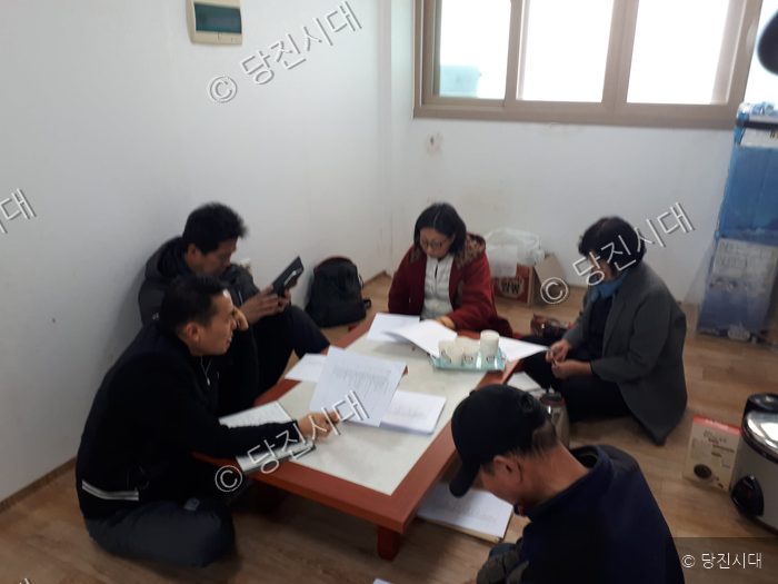 주민들이 모여 서류를 검토하며 회의를 하고 있다.