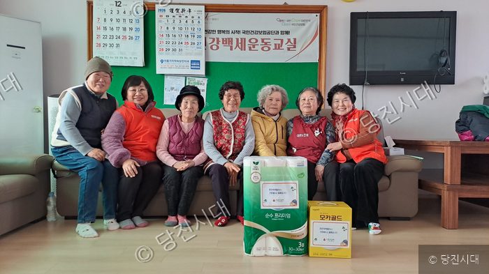 어르신들이 소파에 모여 앉아 생필품 전달 기념촬영을 하고 있다.